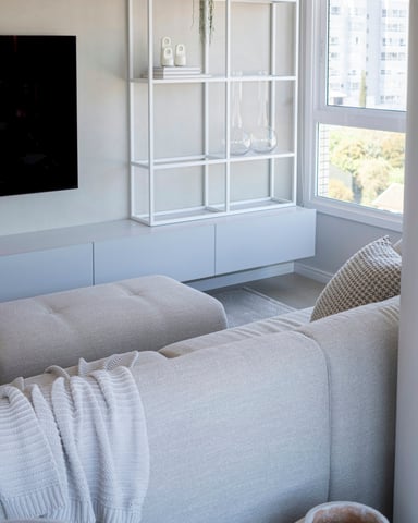Bright white living room with cream sofa, white shelving unit and city views
