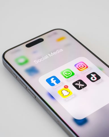 iPhone on white surface showing Social Media folder with Facebook icon