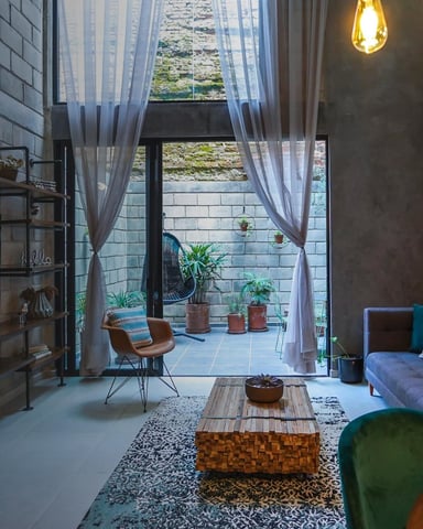 Modern loft living room with exposed brick, open courtyard view, pendant lights, and gallery wall of framed artwork