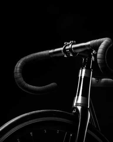 Road bike handlebars and front wheel against black background, black and white photography