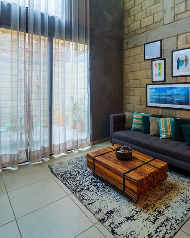 Bright living room with exposed brick wall, sheer curtains, and patio view