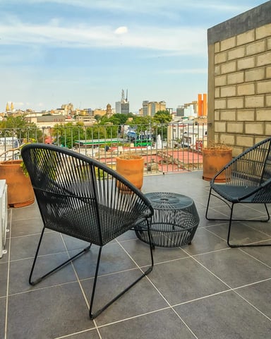Terraza en la azotea con sillas de mimbre y vistas al horizonte de Guadalajara